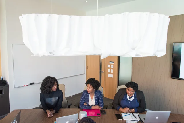 Three women in a modern office engaged in a business meeting with laptops. Five signs an organisation is ready to buy email software, and what each proves