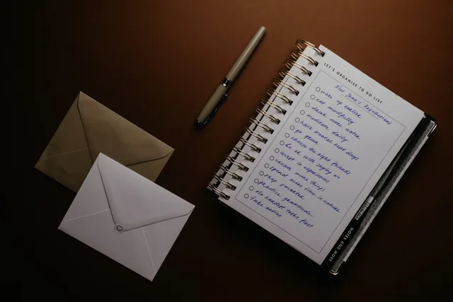 Flat lay of a to-do list, pen, and envelopes on a brown surface, ideal for planning themes. Quality checks to run on suppression, claims and rollback before an email release