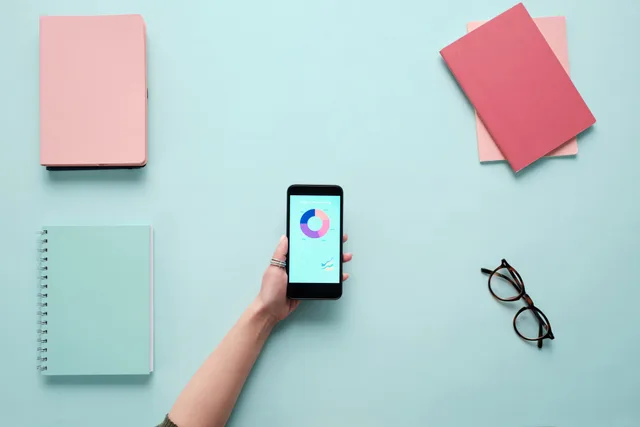 Minimalist flat lay with a smartphone displaying charts, surrounded by notebooks and glasses on a blue background. Email marketing software ROI: a worked model in contribution, not gross turnover