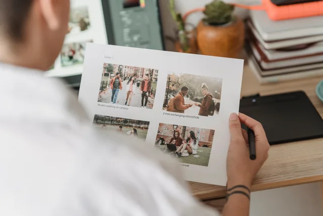 High angle of crop anonymous female photographer with printed pictures working at table with netbook. Email marketing software review methodology: gates first