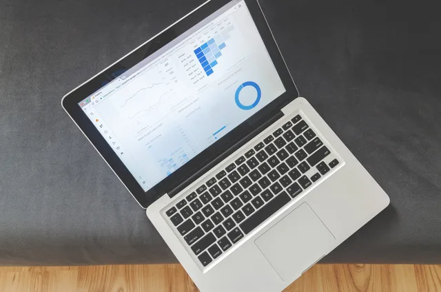 Overhead view of a laptop showing data visualizations and charts on its screen. Choosing email software from the workflow up, with the buying gates kept apart